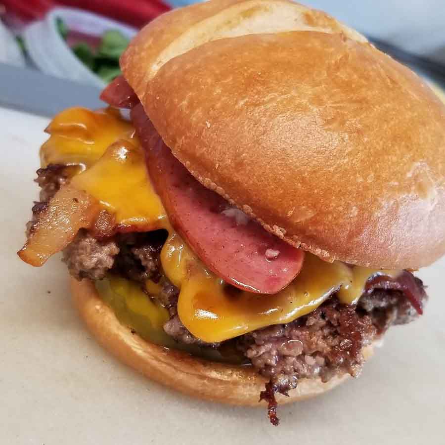 SmokeyJ Burger - Blue J's Rollin' Grill SmokeyJ - Signature patty, smoked bacon, smoked sausage, pickles, cheese and house smokey aioli sauce
